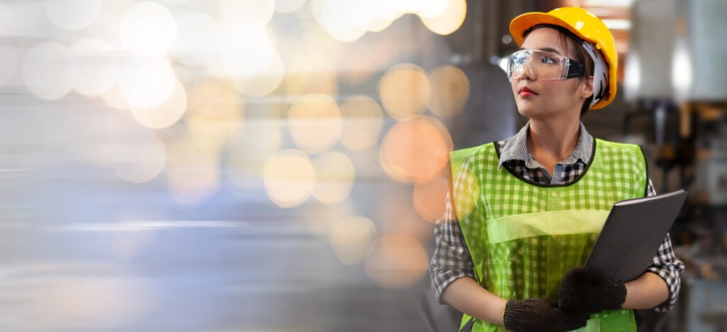 Female technician in safety gear holding a tablet during Robotics Training & Automation Workforce Integration, representing skilled workforce development in smart manufacturing.