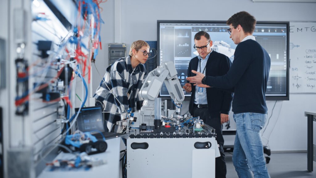 Group of engineers and students engaged in robotics training programs, working on a robotic arm prototype as part of robotics skills training, workforce development in robotics, and industrial robot courses.