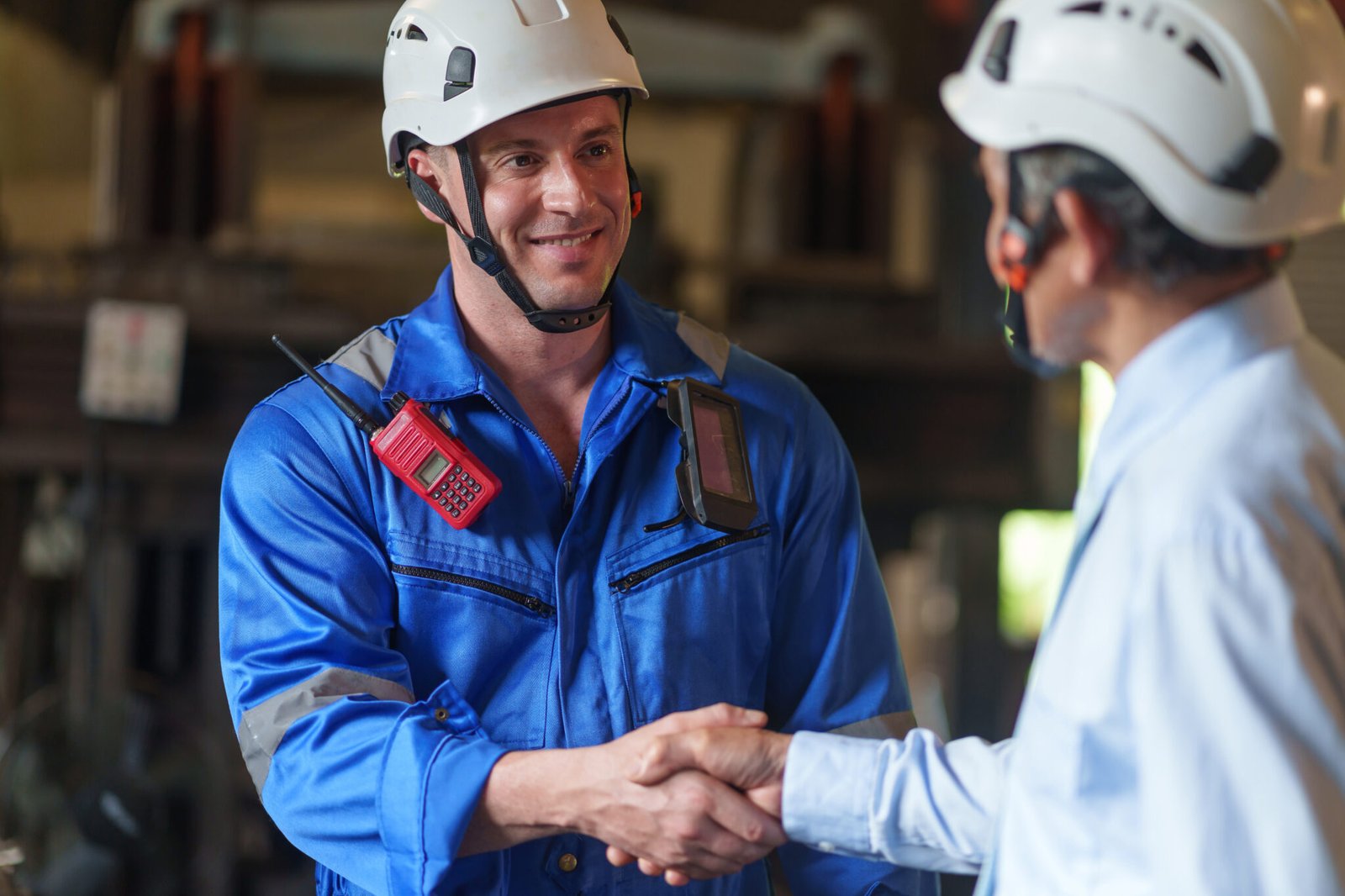 Engineer in blue uniform shaking hands with a supervisor during a Robot Safety Audits & Risk Assessment review, representing teamwork in industrial safety operations.