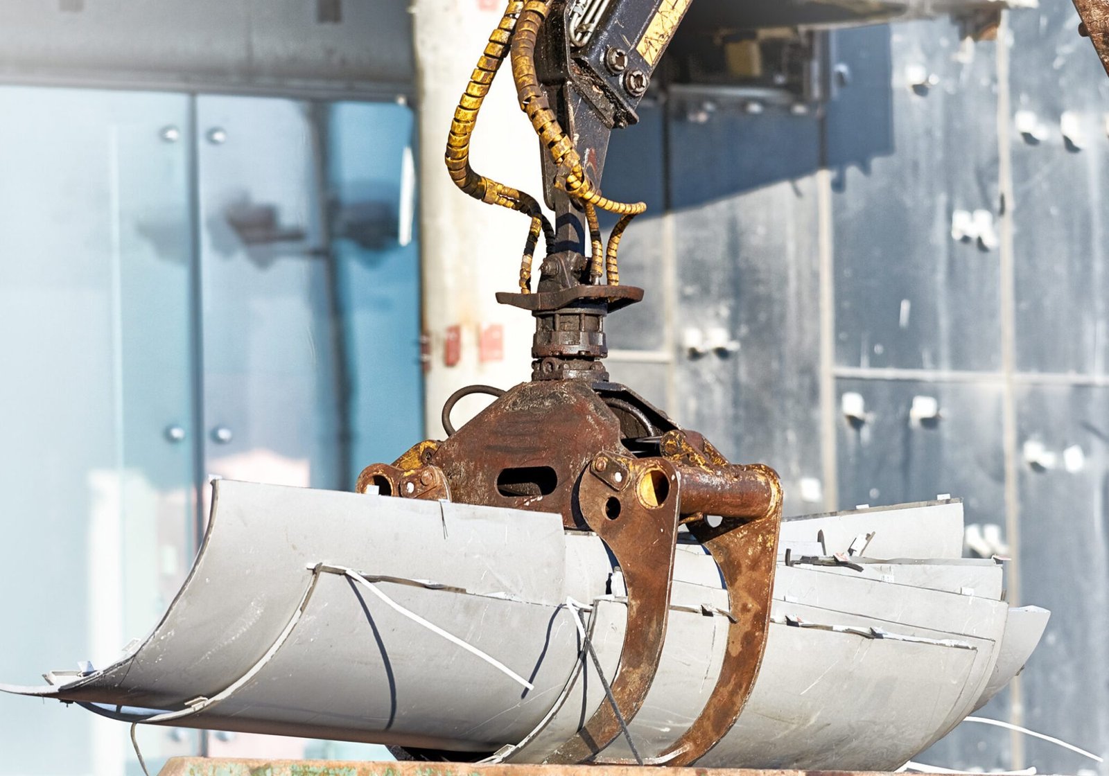Construction robot crane arm lifting building waste into a trash container at an urban site, powered by Recycling & Waste Management Robotics.